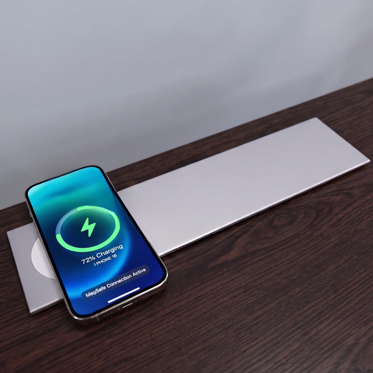 An iPhone actively charging on the built-in wireless pad of the closed Ebco Slide-Out Electric Box, demonstrating seamless desk integration.   