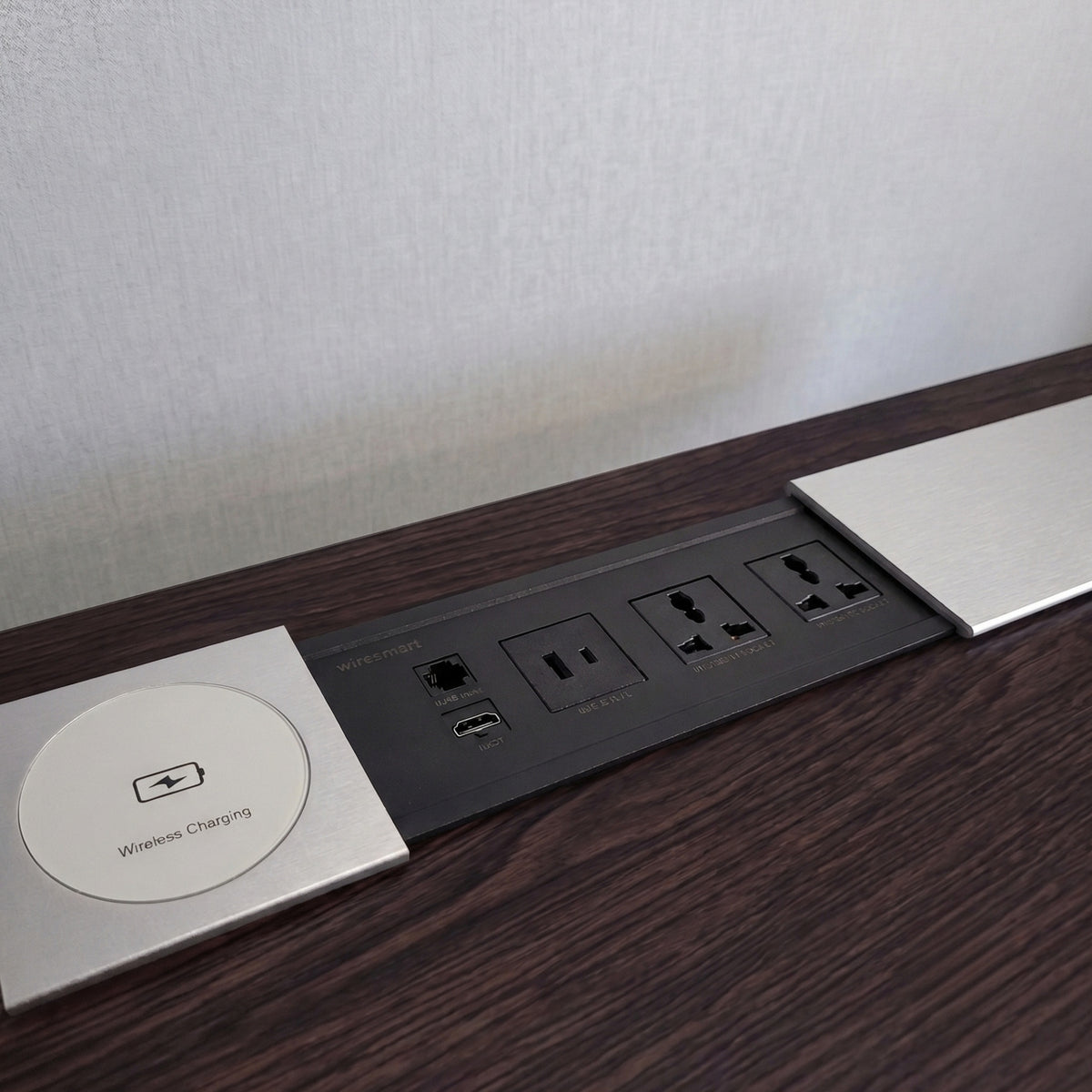Ebco slide-out electric box in the open position, revealing universal power sockets, USB charging ports, and a wireless charger on a dark wood desk.   