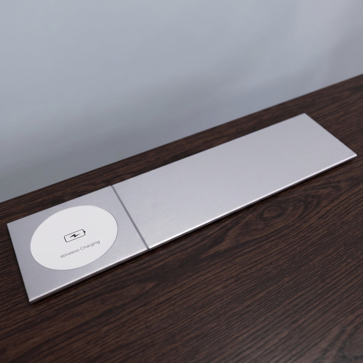 Ebco concealed slide-out electric box in closed position, highlighting the built-in wireless charging pad and sleek silver finish on a dark wood surface.
