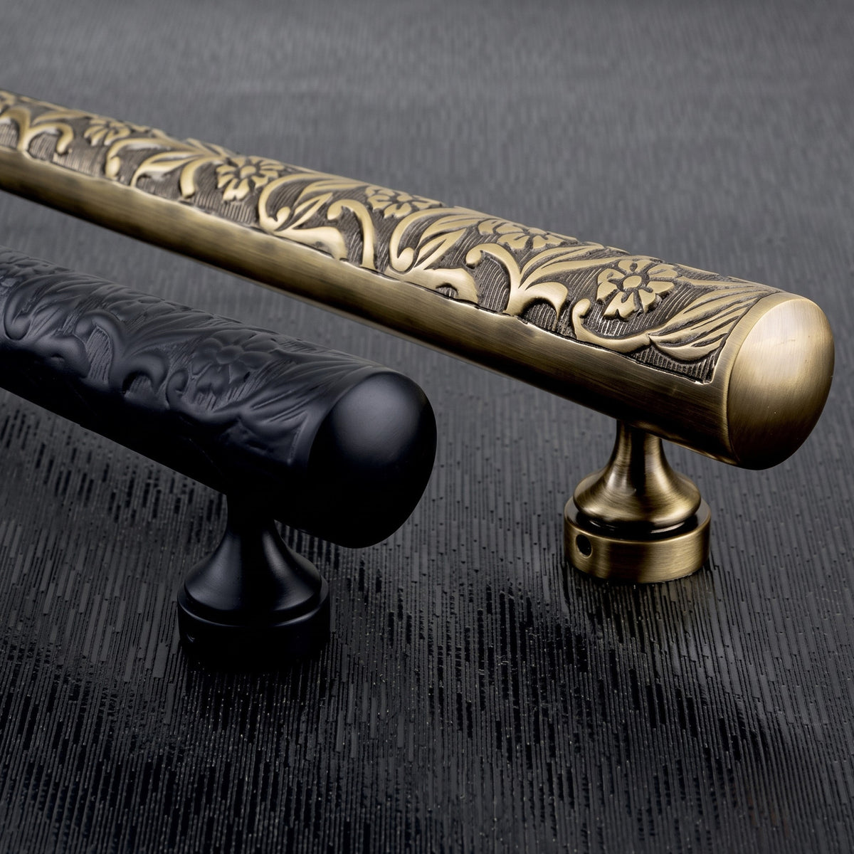 Detailed close-up showing the floral embossed craftsmanship on the antique brass and matte black Jewel Collection door pull handles from Hardware Depot.