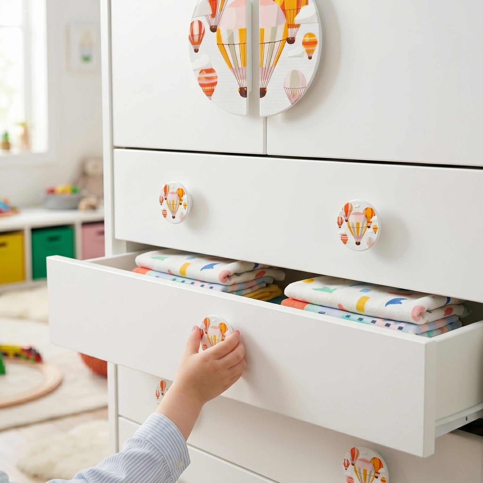 Matching circular acrylic hot air balloon drawer knobs installed on a nursery chest of drawers at SS Hardware.