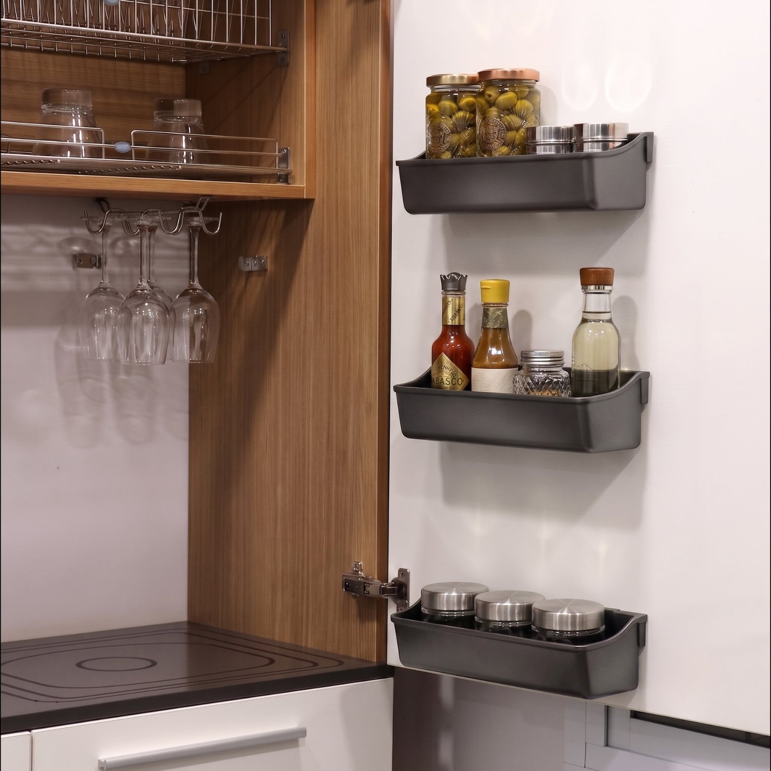 Anthracite clip-on shelf trays mounted on modular kitchen shutter storing sauce bottles and spice jars