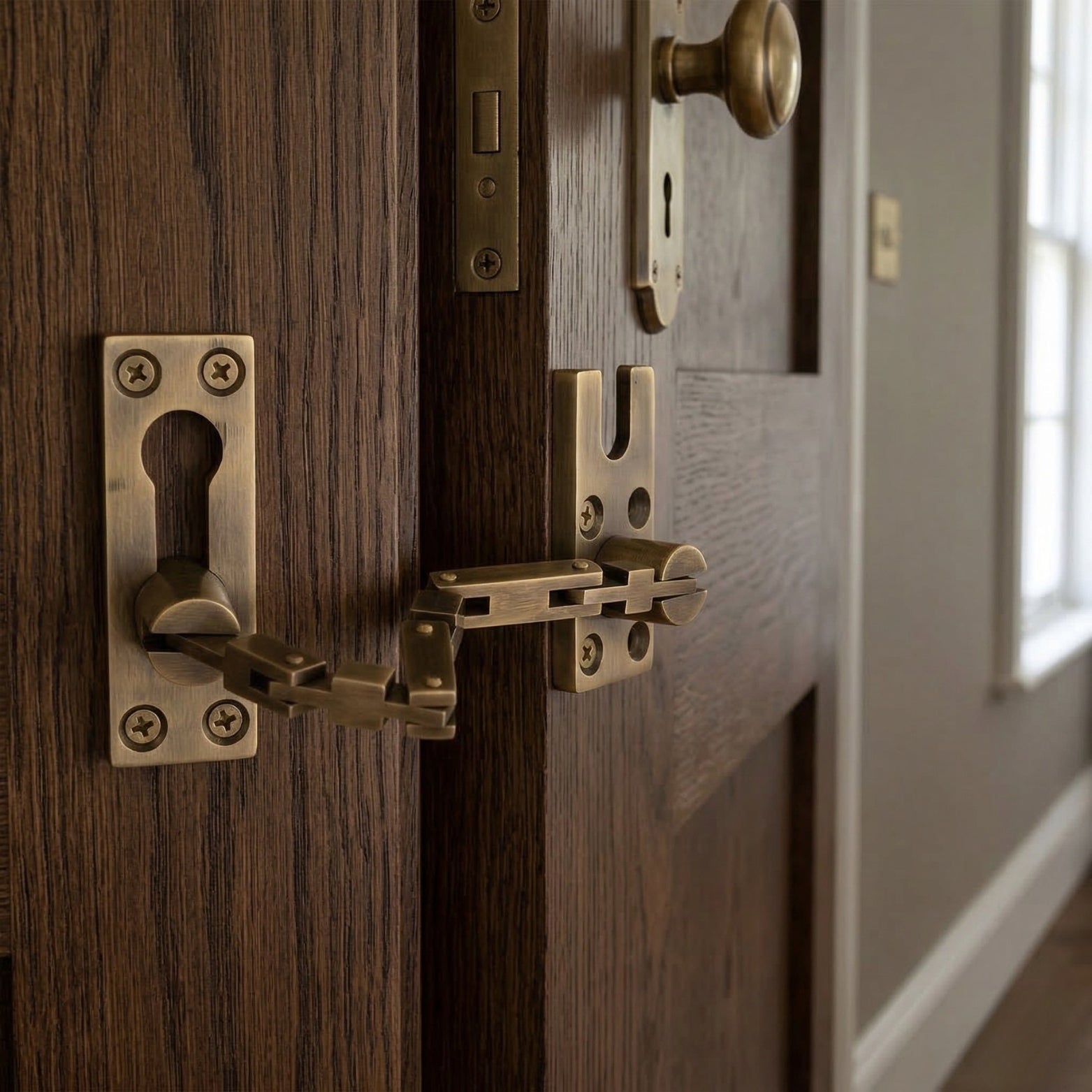 Solid brass security door guard with articulated links in antique brass.