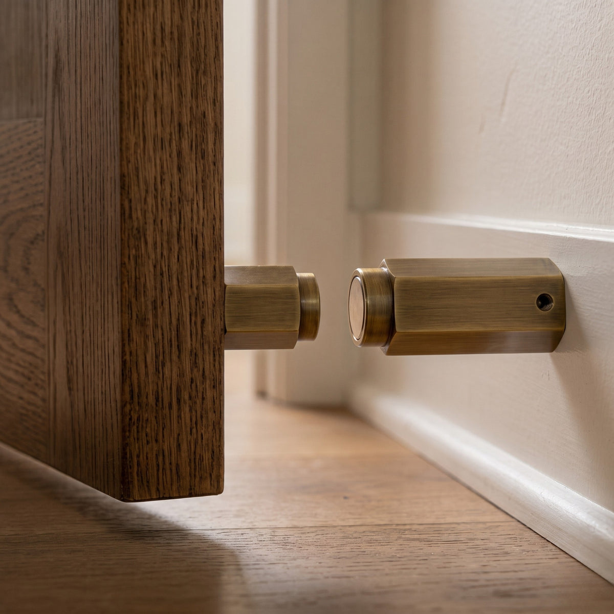 Hexagonal antique brass magnetic door stop installed flush at 90-degree angle on skirting board Hardware Depot BLR