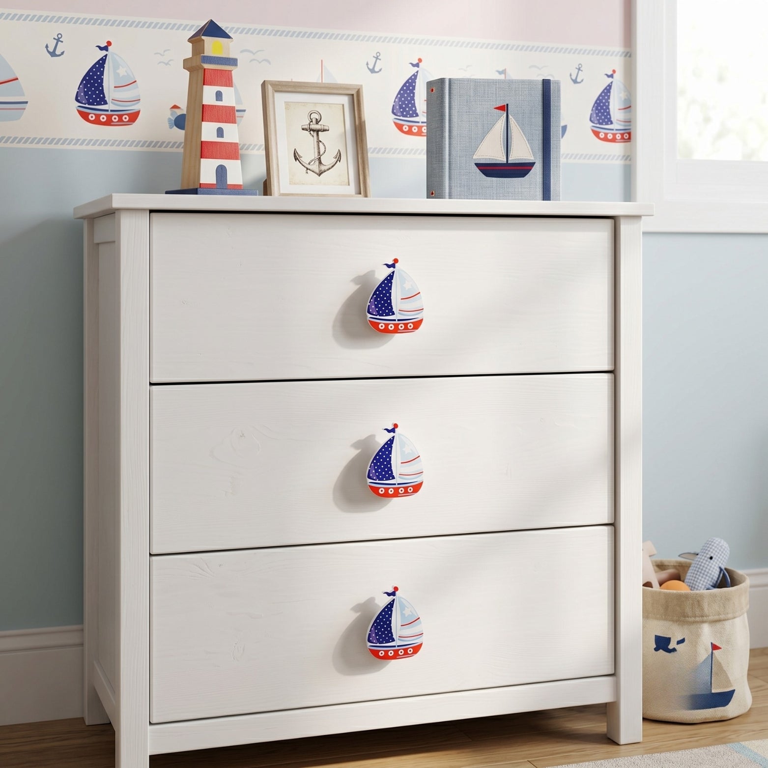 Three sailboat themed acrylic dual mount handles installed on a white modular nursery chest of drawers