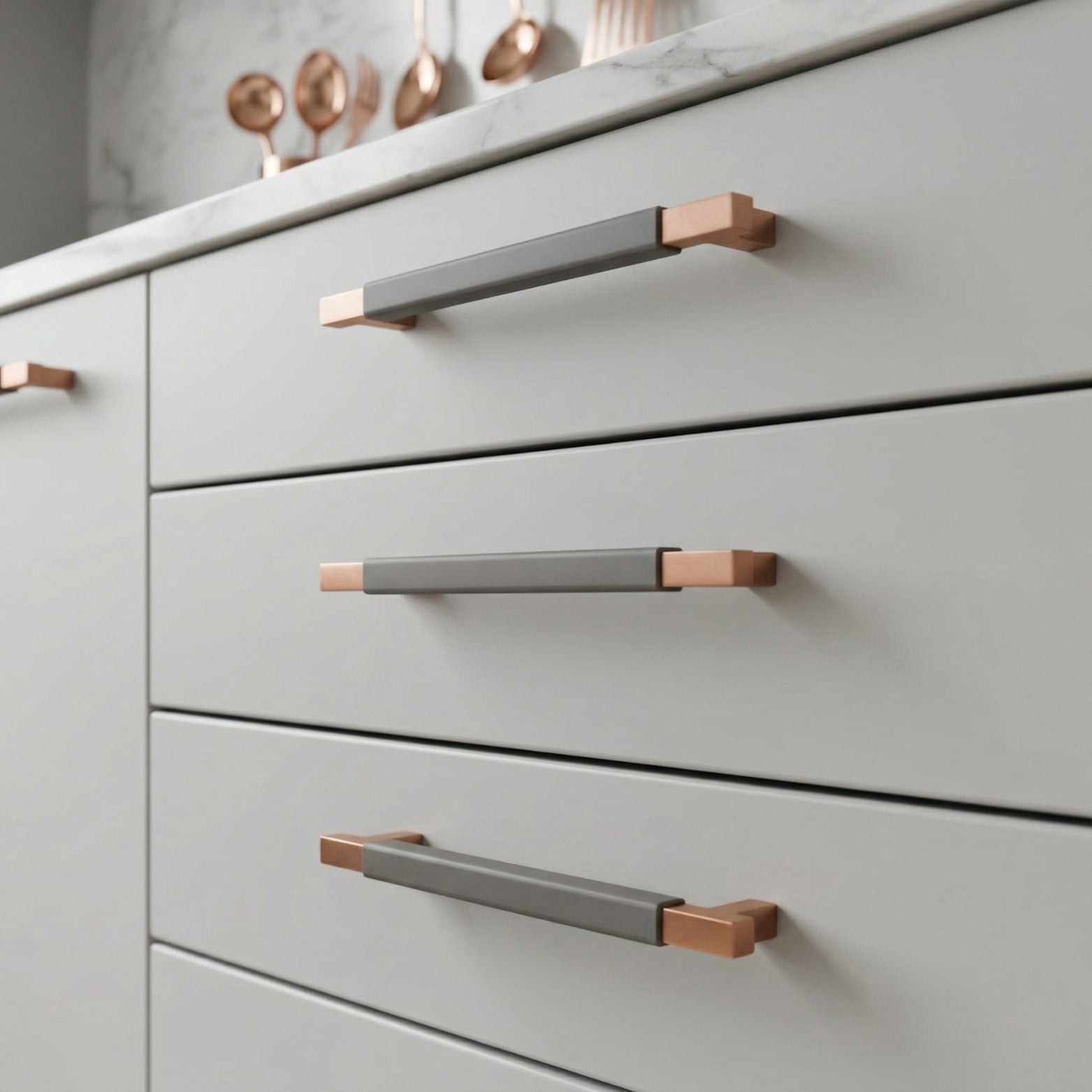 Modern light grey cabinet drawers with premium rose gold and textured grey T-bar handles, featuring copper accents and installed in a luxury kitchen.