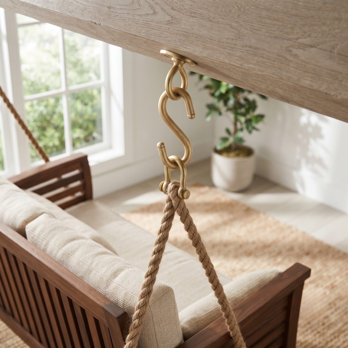 Solid brass heavy duty S hook installed holding a wooden porch swing in an interior residential setting